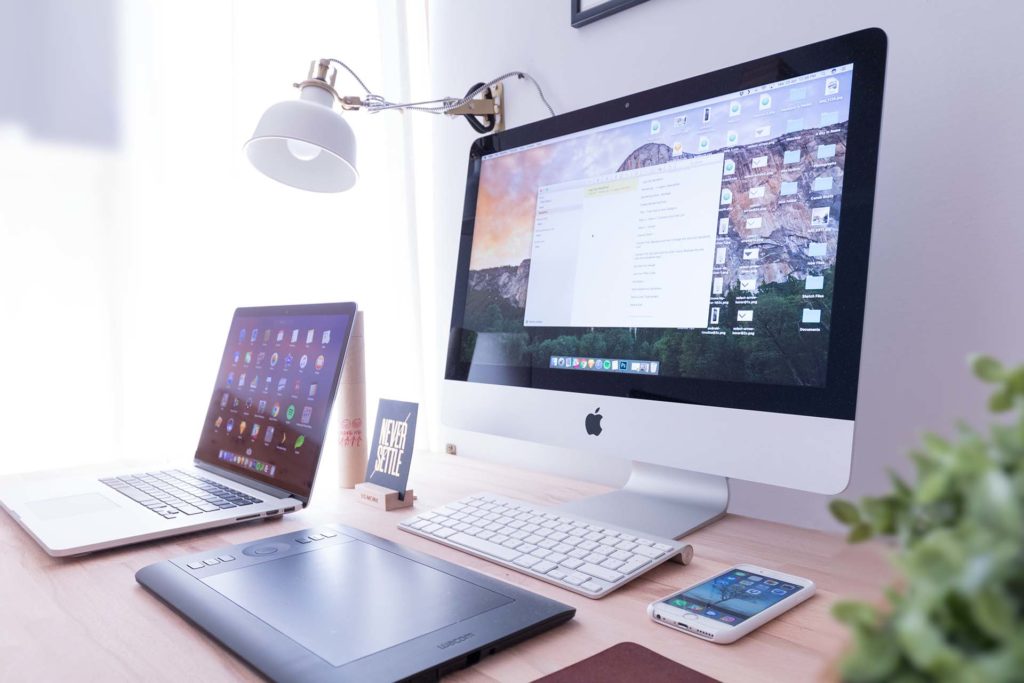 Laptop, monitor, keyboard, tablet, and phone on the desk